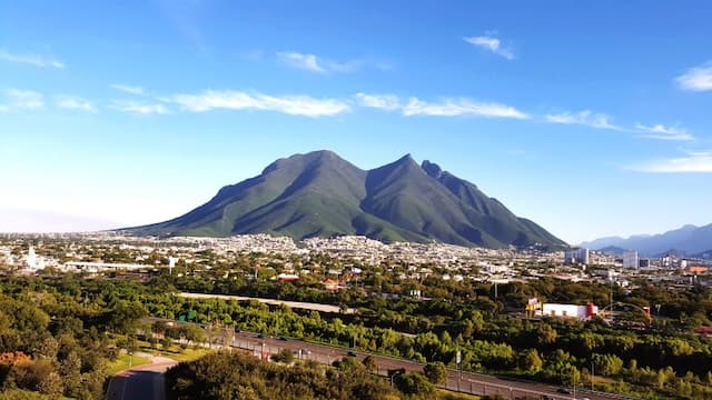 Vista de una montaña verde bajo un cielo azul despejado, representando un paisaje natural.