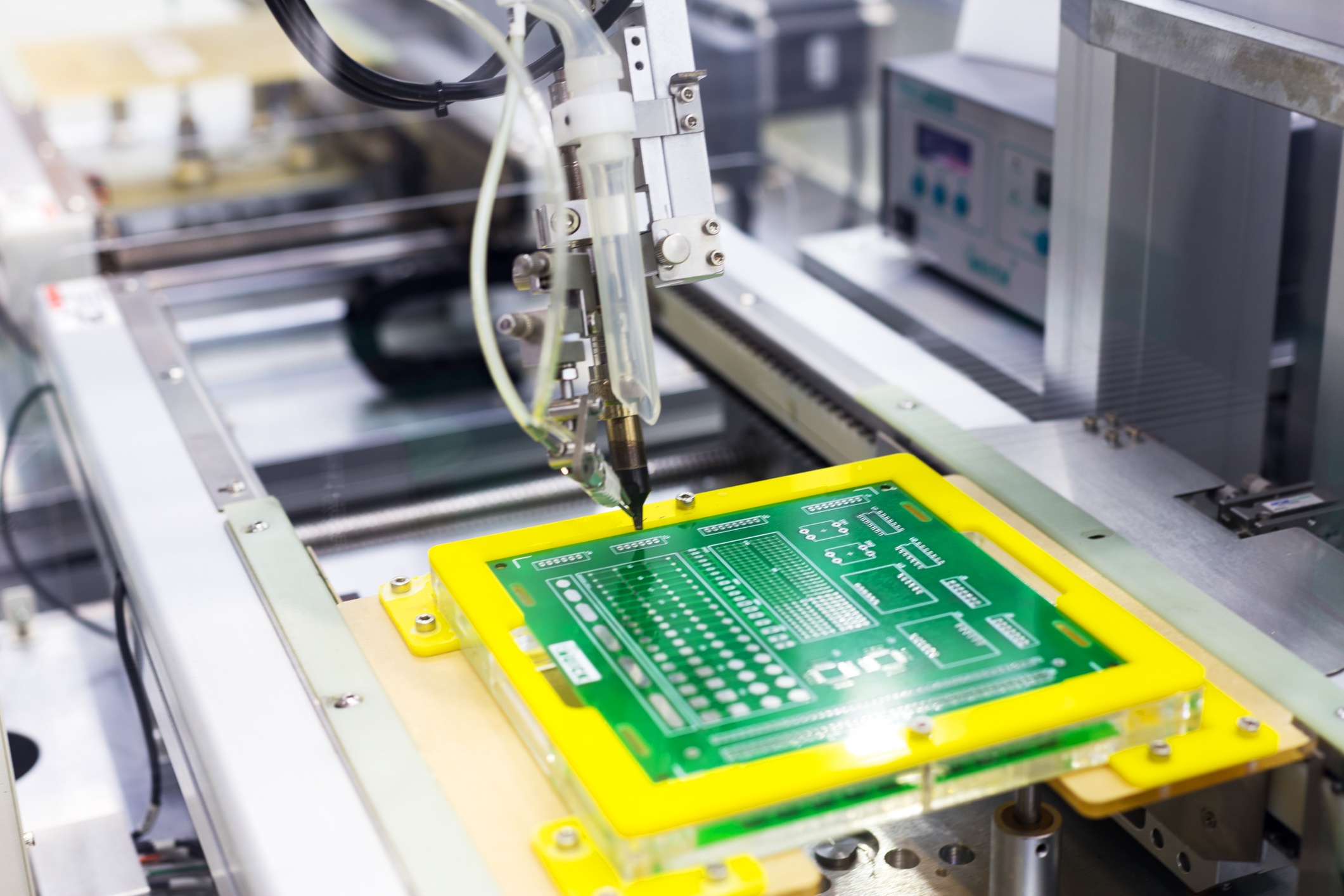 Máquina perforando placas electrónicas en una planta industrial